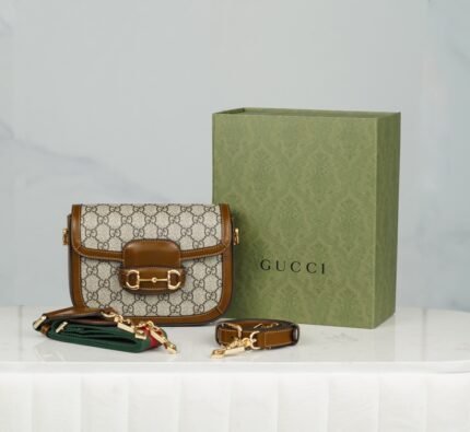 Horsebit 𝟏𝟗𝟓𝟓 Mini Handbag Brown nn Detachable shoulder straps add a mix-and-match look to this vintage-inspired collection. nThis mini handbag comes with two different straps, one in the same color leather for an understated elegance, and the other in red and green webbing for a strong brand identity. The bag is crafted from double G monogrammed canvas with brown leather piping. nSize: 20.5*14.5*5cmnModel No.: 658573