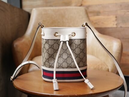 𝐎𝐩𝐡𝐢𝐝𝐢𝐚 Collection Mini 𝐆𝐆𝐆 Bucket bag white n The nOphidia collection is revitalized in Gucci's Aria - Fashion Aria collection, with vintage-inspired details that echo classic brand elements. Sleek and stylish, this mini bucket bag is crafted from beige and ebony GG Supreme canvas and trimmed with classic white leather piping. The red and blue striped webbing appliqué detail pays homage to the brand's equestrian roots and completes the look. nSize: 15.5*19*9cmnModel No.: 550620